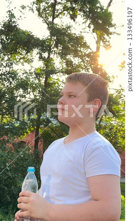 BABY BOY DRINKING WATER AT SUNSET PARK, DRINKING HEALTH REGIMEN, White shirt and hydration, Bottled water moment, Smile and drink break, Trees and sunlight filter, Hot day refreshment, Shade and rest BABY BOY DRINKING WATER AT SUNSET PARK, DRINKING HEALTH REGIMEN, White shirt and hydration, Bottled water moment, Smile and drink break, Trees and sunlight filter, Hot day refreshment, Shade and rest 133496197