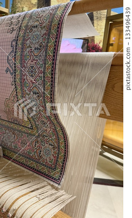 Carpet weaving loom with intricate design and threads in background Carpet weaving loom with intricate design and threads in background 133496439