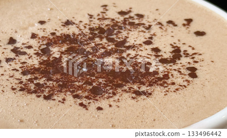 Hot chocolate with cocoa powder sprinkled on foamy surface, perfect for cozy holiday background Hot chocolate with cocoa powder sprinkled on foamy surface, perfect for cozy holiday background 133496442