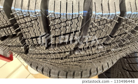 Tire tread close-up showing detailed pattern and metal studs for improved winter traction 133496448