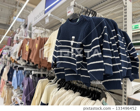 Childrens clothing on display in retail store aisle, showcasing various styles and colors Childrens clothing on display in retail store aisle, showcasing various styles and colors 133496452