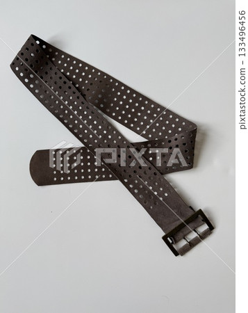 Brown leather belt with perforated design on white surface, suitable as fashion accessory background Brown leather belt with perforated design on white surface, suitable as fashion accessory background 133496456