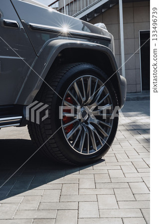Luxury SUV parked on modern pavement with gleaming alloy wheels at a contemporary location 133496739