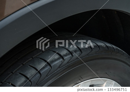 Close-up view of a car tire showcasing tread pattern and wheel design 133496751