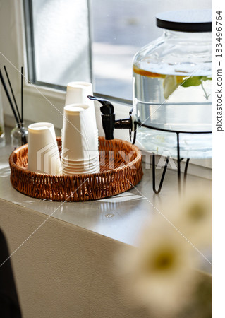 Empty white cups and water dispenser in a cozy cafe setting during the day 133496764
