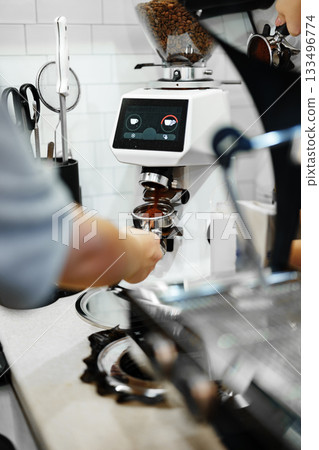Barista prepares espresso with coffee machine in a cozy cafe setting during the morning rush 133496774