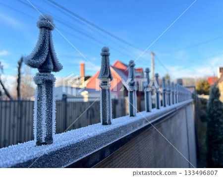 Frost-covered fence of a house on a sunny frosty winter day Frost-covered fence of a house on a sunny frosty winter day 133496807
