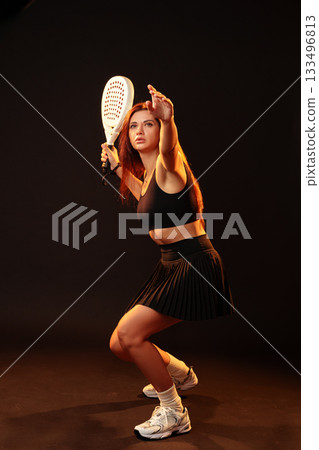 Young woman preparing to serve in a competitive racket sport during a studio session 133496813