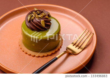 Pistachio cake or tart topped with green mousse with nuts and fruit filling. Pistachio pie 133496863