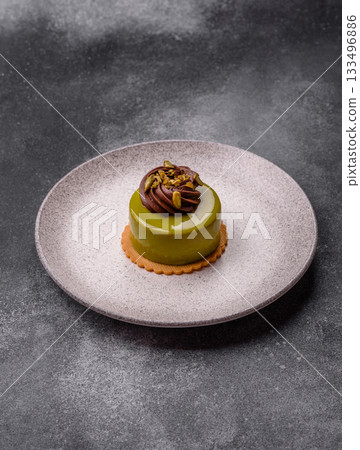 Pistachio cake or tart topped with green mousse with nuts and fruit filling. Pistachio pie 133496886