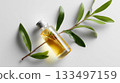 Bottle of essential oil next to green leaves on a light surface in a calming setting 133497159