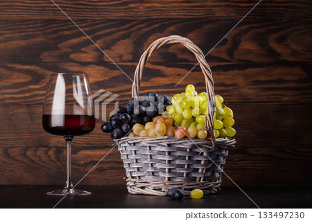 Red wine glass and basket of fresh grapes 133497230