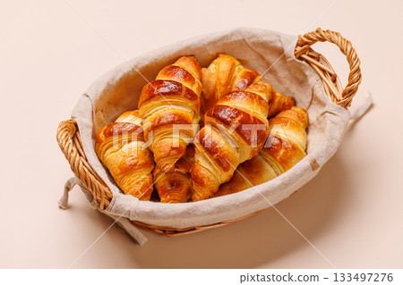 Freshly baked croissants in wicker basket on light background 133497276