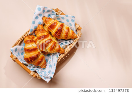 Freshly baked croissants in wicker basket on light background 133497278