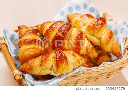 Freshly baked croissants in wicker basket on light background 133497279
