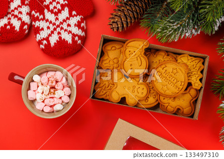 Gingerbread cookies, cup with marshmallows and snowy fir branches 133497310