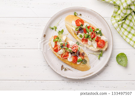 Tasty antipasto toasts featuring classic caprese with mozzarella and tomatoes, and savory prosciutto with herbs Tasty antipasto toasts featuring classic caprese with mozzarella and tomatoes, and savory prosciutto with herbs 133497507
