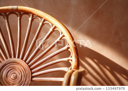 Rattan chair casting delicate shadows on a wall Rattan chair casting delicate shadows on a wall 133497970
