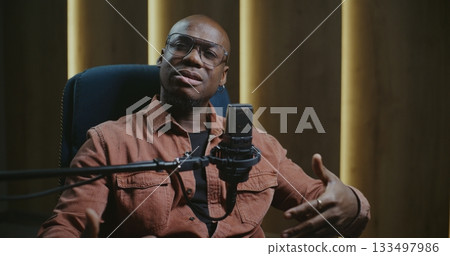 Positive Male Speaker in Professional Audio Studio, Speaking Into Microphone With Confident and Open Expression 133497986
