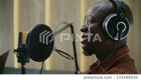 Smiling Podcast Guest Talking Into High Quality Studio Microphone 133498030