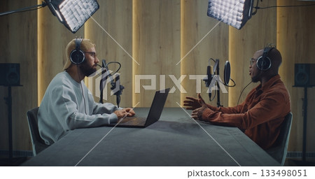 Bearded Podcast Host Using Laptop While Interviewing Guest Across Table Bearded Podcast Host Using Laptop While Interviewing Guest Across Table 133498051