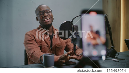 Smartphone Capturing African American Guest Mid Discussion Talks, Gestures Toward Studio Microphone Smartphone Capturing African American Guest Mid Discussion Talks, Gestures Toward Studio Microphone 133498054