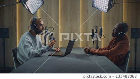 Bearded Podcast Host Using Laptop While Interviewing Guest Across Table Bearded Podcast Host Using Laptop While Interviewing Guest Across Table 133498068