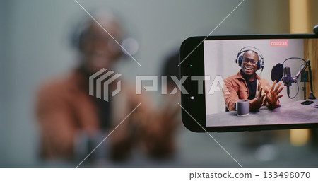 Male Podcast Guest Speaks Expressively as Smartphone Records Talk in Horizontal Close Up 133498070