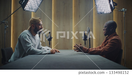 Two Men Recording Engaging Conversation in Modern Podcast Studio Two Men Recording Engaging Conversation in Modern Podcast Studio 133498152