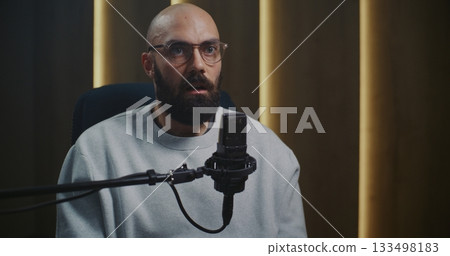 Bearded Male Podcaster or Expert Speaker in Glasses Speaking Into Professional Microphone 133498183