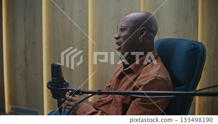 Expert Speaker With Glasses and Earring, Positioned Professional Microphone in Modern Audio Studio 133498190