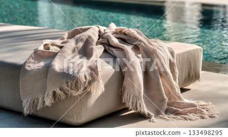 Soft blanket resting on a sunbed by a poolside Soft blanket resting on a sunbed by a poolside 133498295
