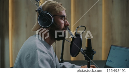 Podcast Host With Tattoo on Neck Engages in Live Recording, Speaking Into Microphone With Pop Filter Podcast Host With Tattoo on Neck Engages in Live Recording, Speaking Into Microphone With Pop Filter 133498491