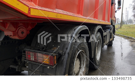 Close-up of the rear wheel of a red cargo truck. Headlights and wheels of the car. 133498735