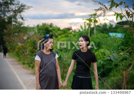 Grandma and granddaughter walk together in the park 133498967