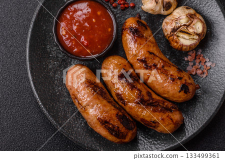 Grilled chicken or beef sausages with sauce and spices. Grilled sausages 133499361