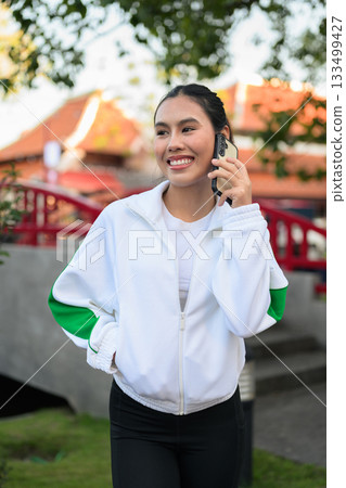 Young Asian Woman in Sporty Casual Outfit Outdoors in Traditional Garden Young Asian Woman in Sporty Casual Outfit Outdoors in Traditional Garden 133499427