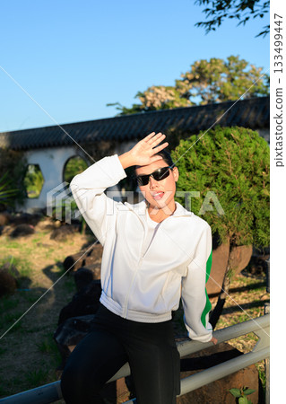 Young Asian Woman in Sporty Casual Outfit Outdoors Wearing Sunglasses 133499447