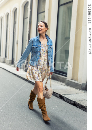 Portrait young adult pretty happy woman woman enjoy have fun walking city street war sunny evening. Denim jacket floral dress sunglasses create vibrant atmosphere filled with festive energy Portrait young adult pretty happy woman woman enjoy have fun walking city street war sunny evening. Denim jacket floral dress sunglasses create vibrant atmosphere filled with festive energy 133499508