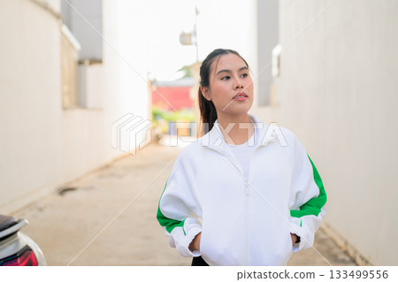 Young Asian Woman in Sporty Casual Outfit Outdoors Young Asian Woman in Sporty Casual Outfit Outdoors 133499556