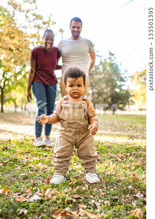 Joyful family moment in the park with a curious toddler exploring 133501395