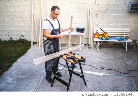 Mature male carpenter working with wooden plank outdoors 133501443