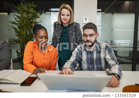 Group of People Standing Around a Laptop Computer 133501529