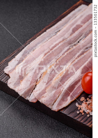 Raw or smoked pork bacon slices or strips as a breakfast ingredient. Raw bacon Raw or smoked pork bacon slices or strips as a breakfast ingredient. Raw bacon 133501732