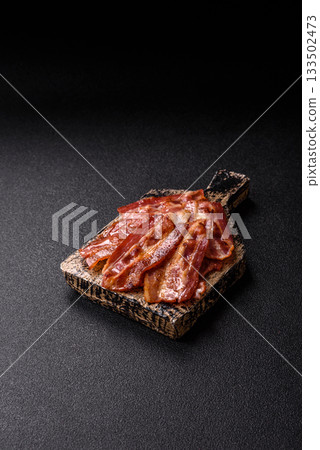Fried pork bacon slices or strips as a breakfast ingredient. Fried bacon Fried pork bacon slices or strips as a breakfast ingredient. Fried bacon 133502473