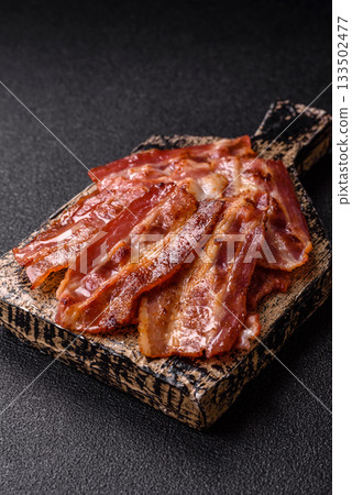 Fried pork bacon slices or strips as a breakfast ingredient. Fried bacon Fried pork bacon slices or strips as a breakfast ingredient. Fried bacon 133502477