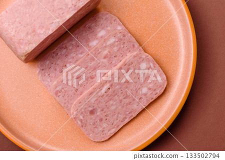 Spiced ham slices, canned meat for lunch sandwiches. Spiced ham as a food background 133502794