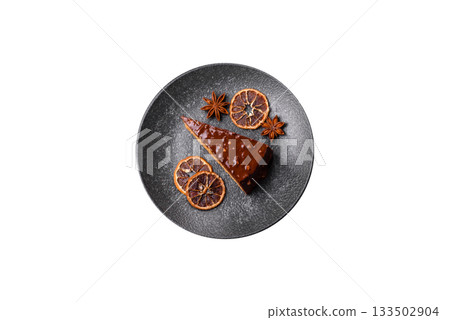 A slice of sweet layered cake covered in chocolate with nuts and caramel. A slice of chocolate cake 133502904