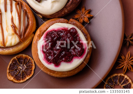 Cinnamon roll, a sweet bun with citrus, cherries, and chocolate, a Danish dessert with cream 133503145