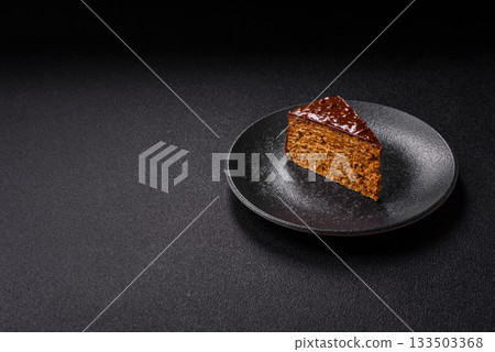 A slice of sweet layered cake covered in chocolate with nuts and caramel. A slice of chocolate cake A slice of sweet layered cake covered in chocolate with nuts and caramel. A slice of chocolate cake 133503368